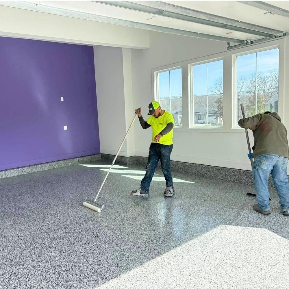 Crew members applying epoxy topcoat in garage